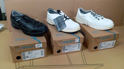Plusieurs paires de chaussures sont posées sur des cartons, sur une table.