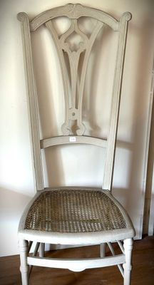 a white chair with a wicker seat in the corner of a room