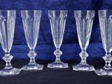 four clear glass goblets are lined up on a black surface