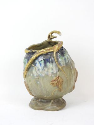 a vase with a handle on a stand on a white surface