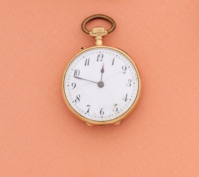 une montre de poche en or posée sur une surface couleur pêche