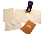 une pile de papiers et une médaille d'or posés sur une surface blanche