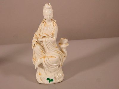 une statue représentant une femme assise sur un tabouret