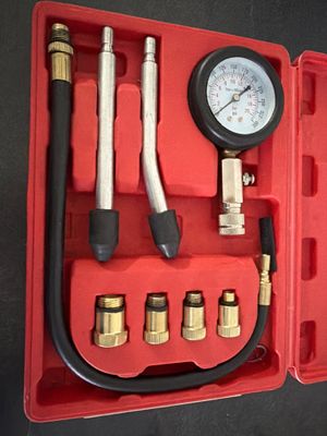 a red case with a gauge and a set of tools in it