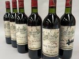 six bottles of wine are lined up in a row on a white surface