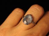 a person ' s hand holding a ring with a blue stone on it