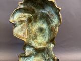 a bronze sculpture of a woman ' s head on a black base