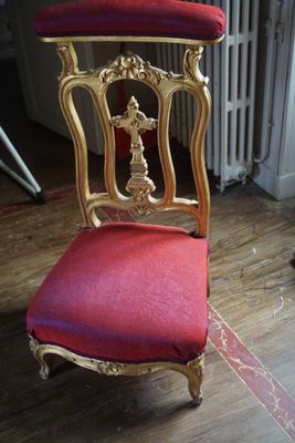 une chaise rouge et dorée sur laquelle est posé un coussin rouge