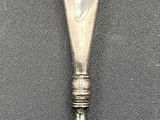 a silver spoon with a silver handle on a gray surface