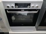 une cuisinière et un four blancs dans un magasin où sont exposés d'autres appareils électroménagers