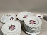 Plusieurs assiettes blanches ornées de fleurs roses sont empilées les unes sur les autres
