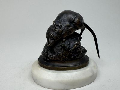 une statue représentant un rat posée sur un socle en marbre