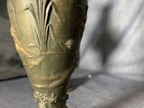 a bronze vase on a wooden base on a table