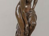 bronze statue of a woman sitting on a rock with her hands on her knees