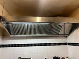 a stainless steel range hood in a kitchen with black and white tiles