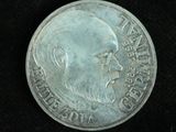 an old silver coin with a man ' s face on it on a black surface