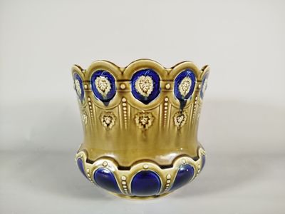 un vase bleu et or posé sur une surface blanche