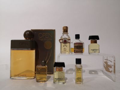 plusieurs flacons de parfum posés sur une table, à côté d'une boîte