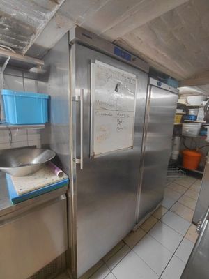 un grand réfrigérateur en acier inoxydable dans une cuisine dotée de nombreux plans de travail