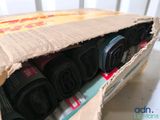 a cardboard box filled with rolled up rolls of fabric