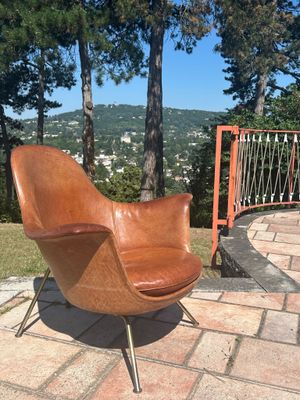 a brown chair sitting on a brick patio next to a fence
