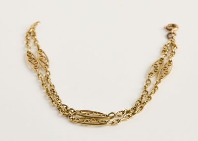 gros plan d'un bracelet en chaîne en or sur fond blanc