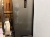 a silver refrigerator and a black trash can in a room