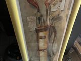 painting of a golf bag and clubs in a frame on the floor