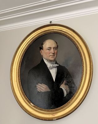 portrait d'un homme en costume noir et nœud papillon, dans un cadre doré
