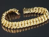 gros plan d'un bracelet en or sur une surface noire
