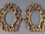 pair of ornate gold oval mirrors on a gray surface