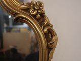a mirror with a gold frame and a flower decoration on it