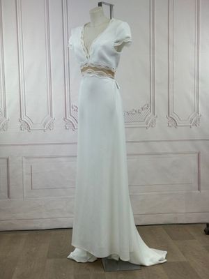 the dress is white and has a gold belt on the waist
