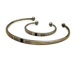 two silver bracelets with black stones on them on a white background