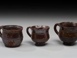 trois tasses marron posées les unes à côté des autres sur une table