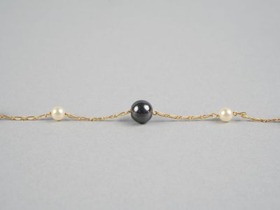 un bracelet composé d'une perle noire et d'une chaîne en or