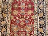 un tapis ancien à fond rouge et bordure dorée