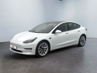 une Tesla Model 3 blanche garée dans une pièce blanche