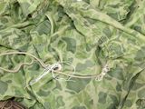 a green and white camouflage fabric with a pair of scissors on it