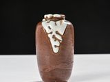 a brown vase sitting on a white table with a black background