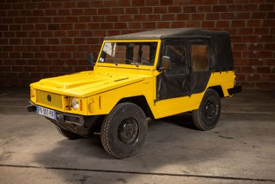 a yellow jeep parked in front of a brick wall