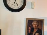 une horloge accrochée au mur au-dessus d'un portrait de femme