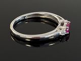 an image of a diamond and ruby ring on a black surface