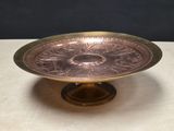 an antique brass plate with a flower design on it on a table