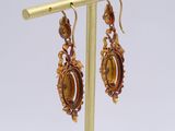 pair of earrings on a gold plated stand on a white background