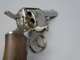 a silver revolver with a wooden handle on a white surface