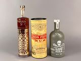 trois bouteilles d'alcool et une bonbonne posées sur une table