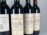 four bottles of red wine are lined up on a white surface