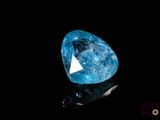 a close up of a blue diamond on a black surface