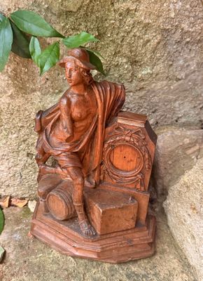une statue représentant un homme assis sur une chaise à côté d'une horloge